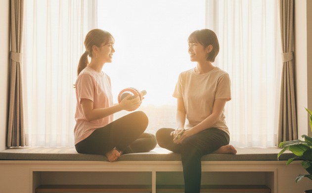 「まとめ:最後にそっと贈る言葉と、設計者としての総括」
あいみと美羽が窓辺で並んで座り、穏やかな笑顔で語り合っている。背景は夕方の柔らかい光。腹筋ローラーは窓際の棚に置かれている。